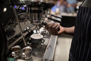 Mid section of waiter making cup of coffee