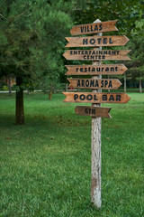 Wooden street signs in the recreation center. Blank street sign post. Crossroad signpost with directions to villas, hotel, entertainment center, restaurant, aroma spa, pool bar and gym