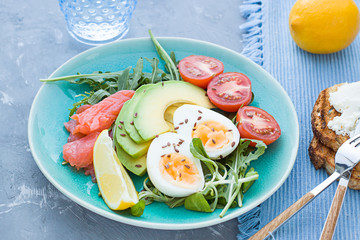 Healthy salad with avocado, corn salad, smoky salmon, eggs and tomatoes for breakfast. Close up