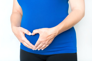Pregnant woman holding her hands in shape of heart on belly