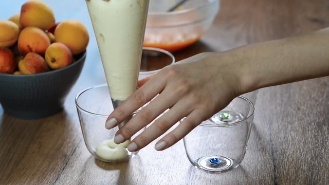 Female hand squeezing the cream from the pastry bag in a glass