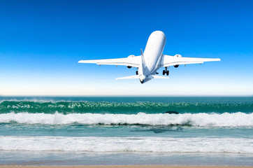 Passenger airplane departure the landing at the airport low over a tropical beach