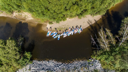 SUP unidentifiable people paddle boarding on a calm river during summer