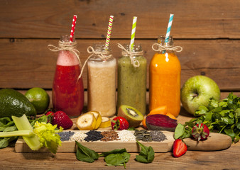Assortment of fruit and vegetable smoothies in glass bottles with straws