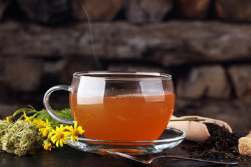 A cup of tea with tea leaves. Tea among the herbs.