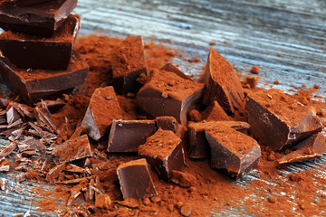 Chocolate cream melted, chocolate pieces and chocolate powder on wooden table