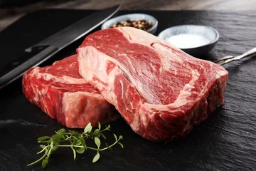 Photo sur Plexiglas Viande Raw fresh meat Ribeye Steak, seasoning and meat fork on dark background