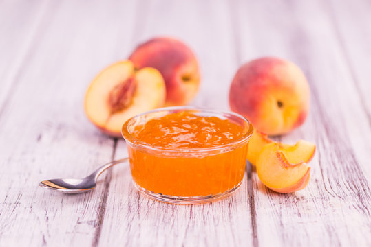Peach Jam on wooden background; selective focus