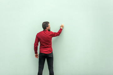 Fototapeta na wymiar Young adult businessman painting on gray wall