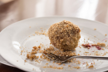 Plum dumplings on the white round plate with fork on the plate with backlight