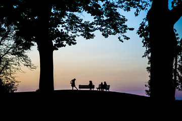 Silhouette of four women on benches in a park