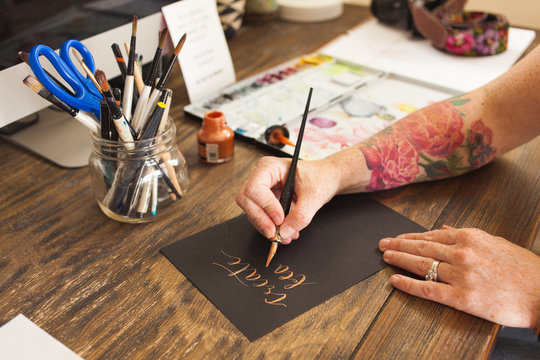 Artist writing caligraphy with paintbrush.