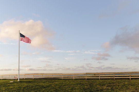 American flag on grassy landscape against cloudy sky