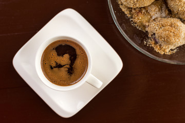Flat lay above white cup of coffee with plum dumplings on the brown wooden table
