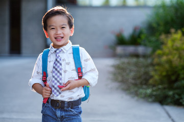 Back to school: Happy Asian kid carrying a backpack in school