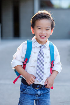 Back to school: Happy Asian kid carrying a backpack in school