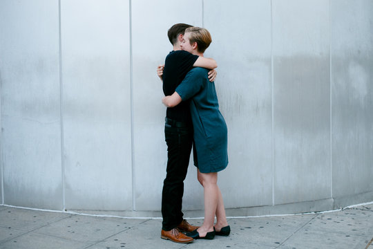 Two women embrace in front of metal wall