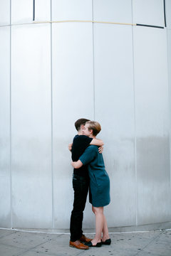 Two women embrace in front of metal wall
