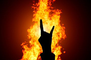 Silhouette of Rock and Roll hand sign against the fire background. - obrazy, fototapety, plakaty