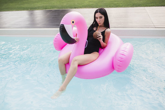 Beautiful Young Woman Floating On A Flamingo Float In A Swimming Pool