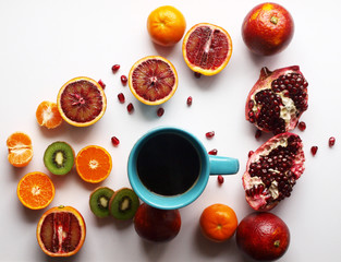 a cup of hot tea around strewn with tropical citrus fruits. summer table, bright fruit, colorful