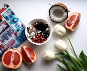 on the table a magazine, an hour with breakfast and sweets, fruits and flowers, coconut and grapefruit. summer relaxed morning with fresh colorful fruits