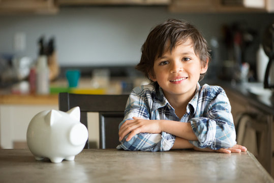 boy smiles after putting coins in his piggy bank