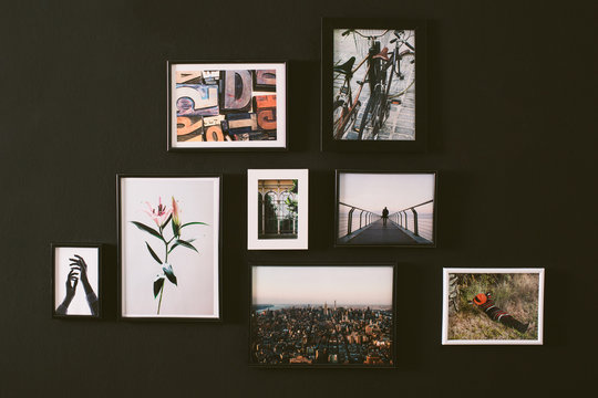 Variety of pictures hanging in a black wall.
