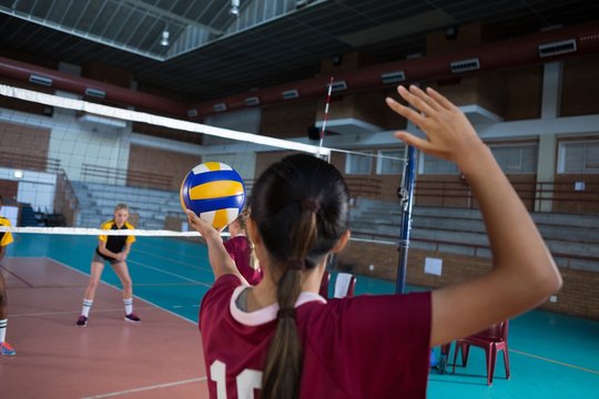 Female players playing volleyball in the court