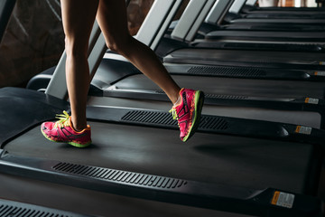 Young woman running on treadmill in gym