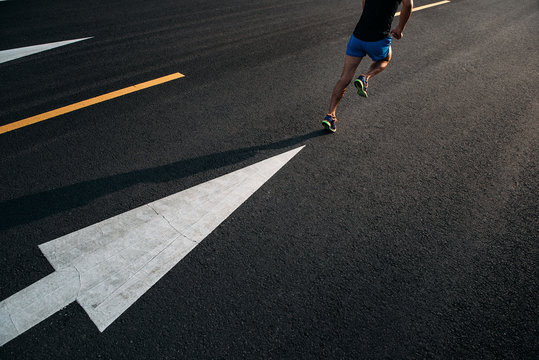 Young man running on road with arrows