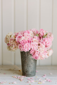 Fading pink rose flowers in an antique metal cup.