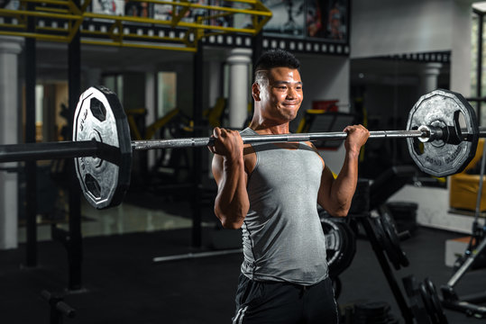 Focused man doing barbell squats at gym