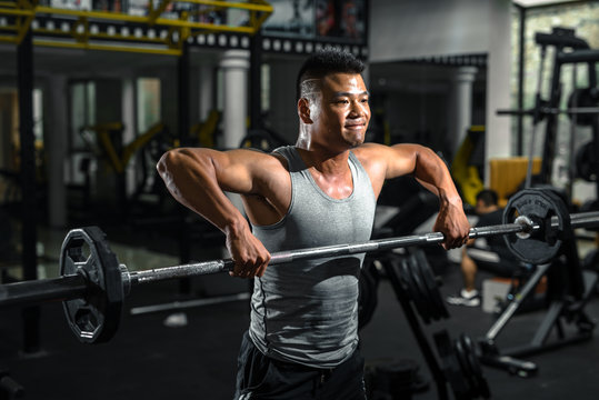 Focused man doing barbell squats at gym