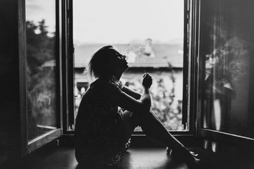 woman smoking in front of a window