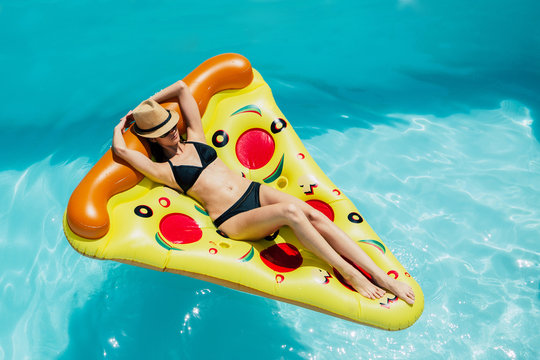 Woman on a pizza float in a swimming pool