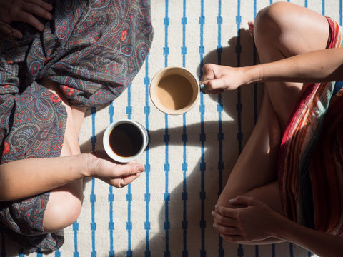 Overhead shot of two women drinking coffee on floor