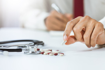 Close-up hand of male doctor holding and showing pills in office