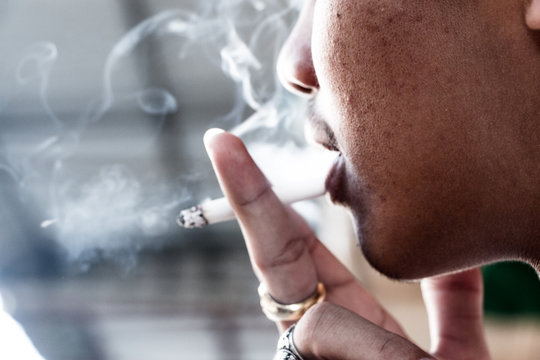 The image of a young man smoking and smoking out of his mouth.