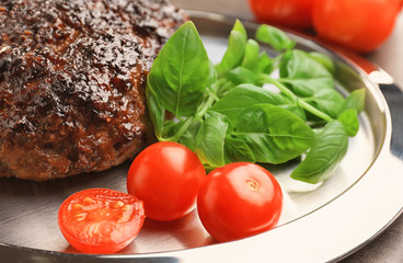 Tasty baked turkey meatloaf with basil and tomatoes on plate, closeup