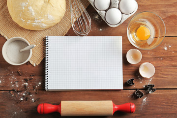 Notebook and raw dough with ingredients on kitchen table. Cooking classes concept