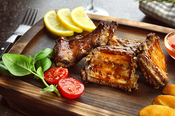 Wooden tray with delicious ribs and vegetables, closeup