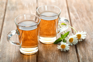 Cups of chamomile tea on wooden background
