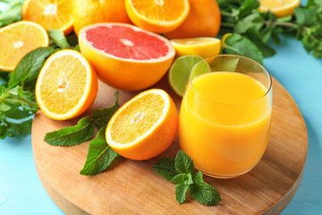 Composition with glass of fresh juice and citrus fruits on wooden board