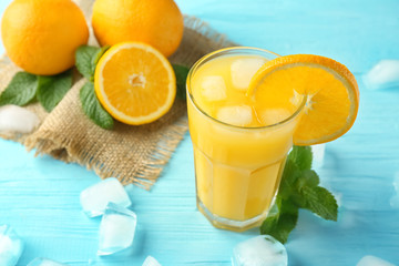 Composition with glass of fresh juice and oranges on wooden table