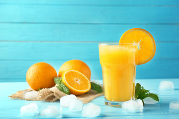 Composition with glass of fresh juice and oranges on color wooden background