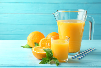 Composition with fresh juice and oranges on color wooden background