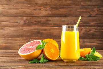 Composition with glass of fresh juice and citrus fruits on wooden table