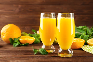 Composition with glasses of fresh juice and citrus fruits on wooden table