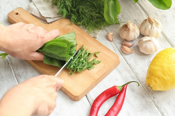 Woman cutting spinach on wooden board